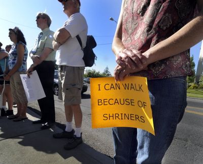 Marie Firestone holds a sign at a Save Our Shriners rally outside the Shriners Hospital for Children in Spokane Thursday. Firestone once was a patient at the hospital.  (Christopher Anderson / The Spokesman-Review)