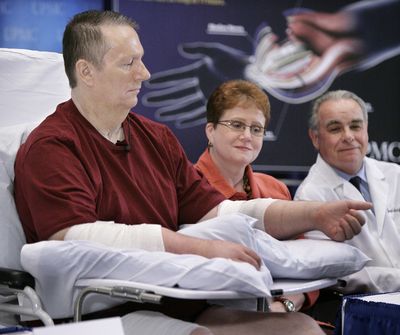 ORG XMIT: PAGP111 Double hand transplant recipient Jeff Kepner, 57, of Atlanta, Ga., left, lifts one of his transplanted hands while wife Valerie, center, and Dr. Joseph Imbriglia look on during a news conference at the University of Pittsburgh Medical Center in Pittsburgh on Thursday, July 16, 2009. (AP Photo/Gene J. Puskar) (Gene Puskar / The Spokesman-Review)