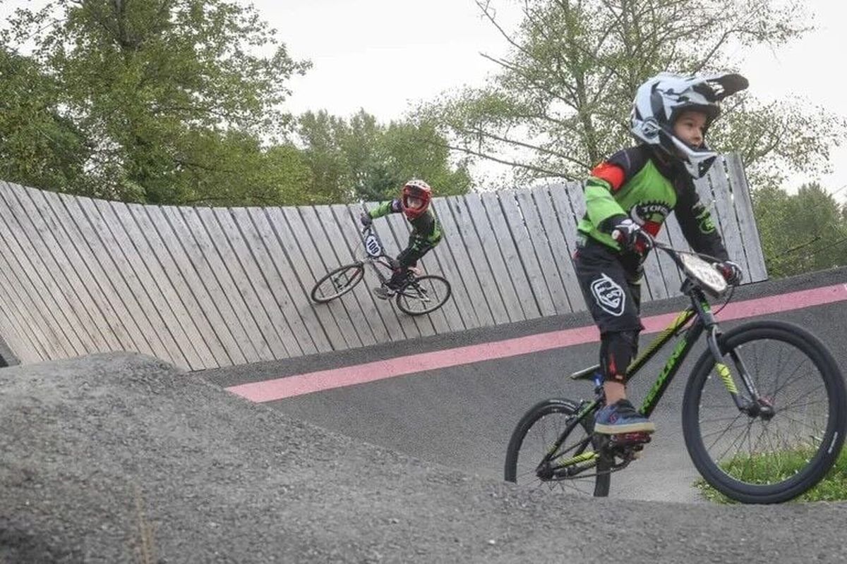 Johnny Novak, right, a member of Toros Cycling Club, rides on a pump track near a BMX track in North SeaTac Park, on Sept. 4.  (Ivy Ceballo/Seattle Times )