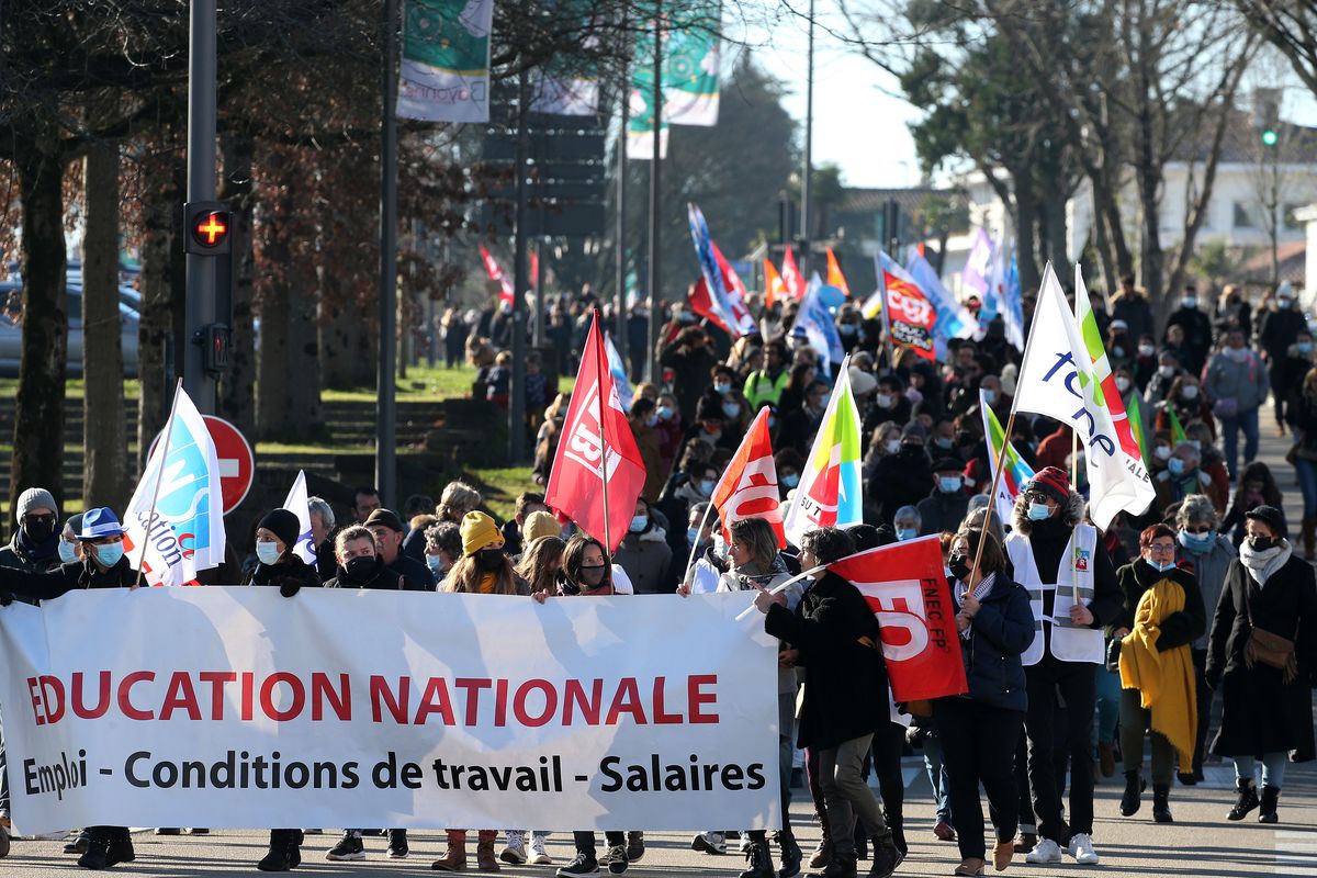 Teachers and students hold a banner reading " National Education- working condition - wages " as they demonstrate in Bayonne, southwestern France, Thursday, Jan. 13, 2022. French teachers have walked out in a nationwide strike Thursday to express anger at the way the government is handling the virus situation in schools, denouncing confusing rules and calling for more protection.  (Bob Edme)