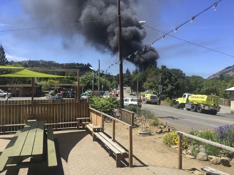 In this photo provided by Silas Bleakley, a train towing cars full of oil sends up a plume of smoke after derailing Friday, June 3, 2016, near Mosier, Ore. The accident happened just after noon about 70 miles east of Portland. It involved eight cars filled with oil, and one was burning. Highway 84 was closed for a 23-mile stretch between The Dalles and Mosier and the radius for evacuations was a half-mile. (Silas Bleakley)