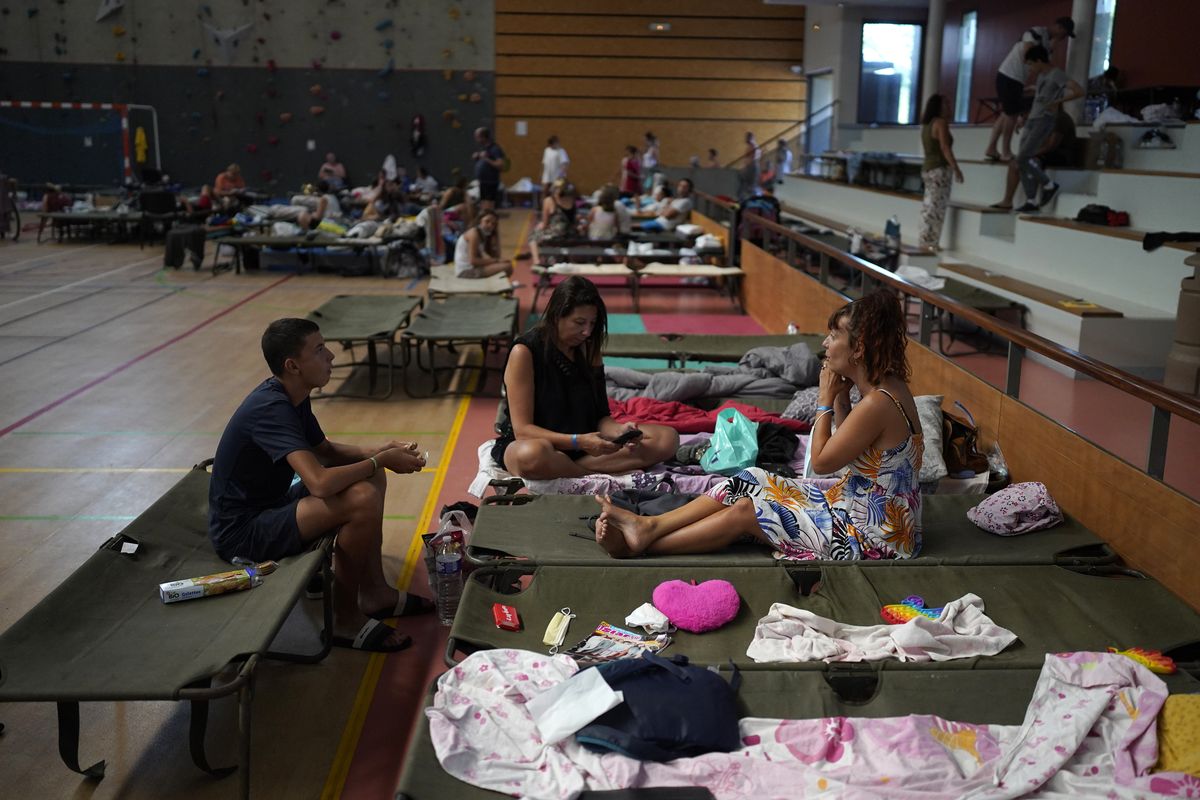 Evacuated campers rest in a gymnasium in Bormes-les-Mimosas, southern France, Wednesday, Aug. 18, 2021. Firefighters have been able to "stabilize" the blaze that raced Tuesday through forests near the French Riviera, forcing thousands of people to flee homes, campgrounds and hotels in a picturesque area beloved by residents and tourists alike.. (Daniel Cole)