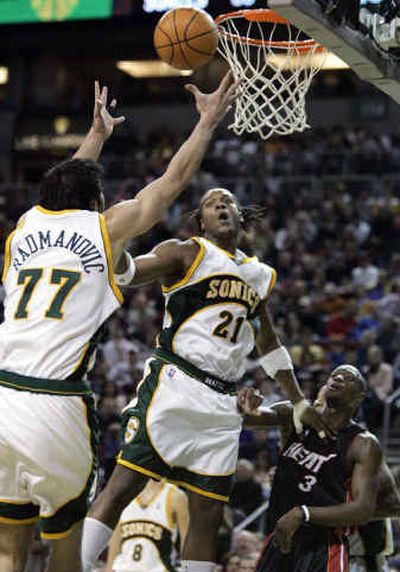
Seattle's Vladimir Radmanovic and Danny Fortson (21) reach for a loose ball over Miami's Dwyane Wade in the second half Sunday. 
 (Associated Press / The Spokesman-Review)