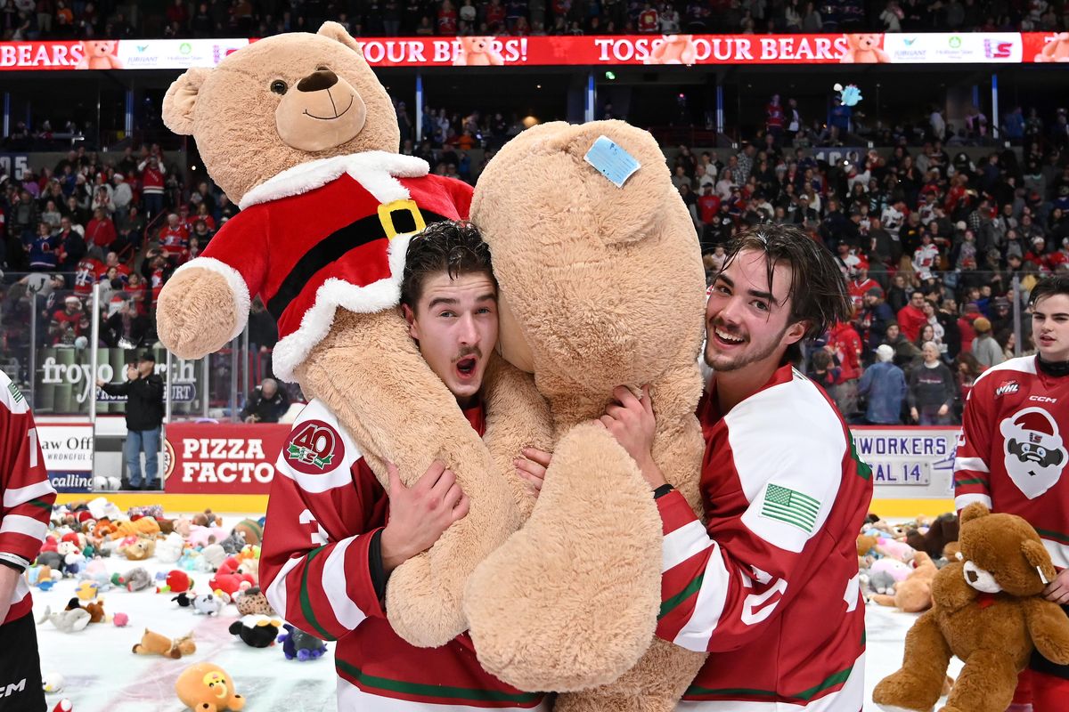 Spokane Chiefs Brayden Crampton, left, and Shea Van Olm carry teddy bears during the first period against the Wenatchee Wild on Saturday at the Arena.  (James Snook/For The Spokesman-Review)