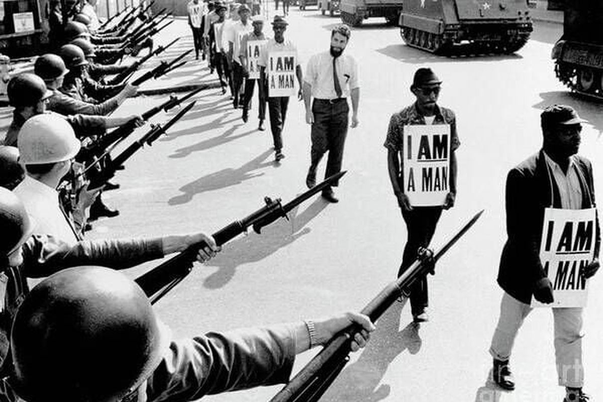 Civil Rights activists are blocked by National Guardsmen brandishing bayonets while trying to stage a protest on Beale Street in Memphis, Tenn. The marching demonstrators, who are wearing signs which say “I Am A Man,” are also flanked by tanks. The Rev. Dr. Kenneth Davis is second from right.  (Getty Images)