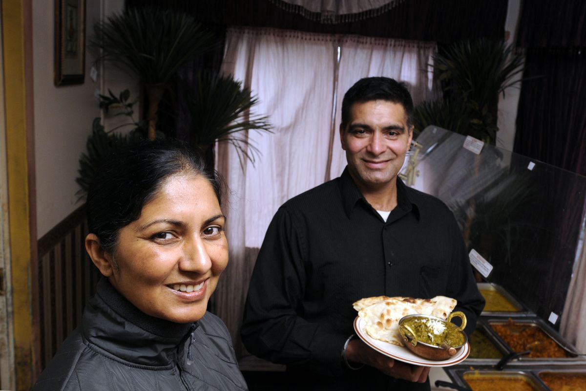 Manjit Kaur, left, owner of the Top of India restaurant, and chef Hira Singh, holding a dish of sag paneer and naan bread, will host a “langar” for the Sikh holiday. Sag paneer is a sauce made of blends of spices, spinach, mustard greens, homemade cheeses and garlic. (The Spokesman-Review)
