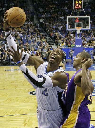 Orlando’s Dwight Howard, left, goes up to shoot against Los Angeles’ Andrew Bynum. Howard had 21 points and 23 boards. (Associated Press)