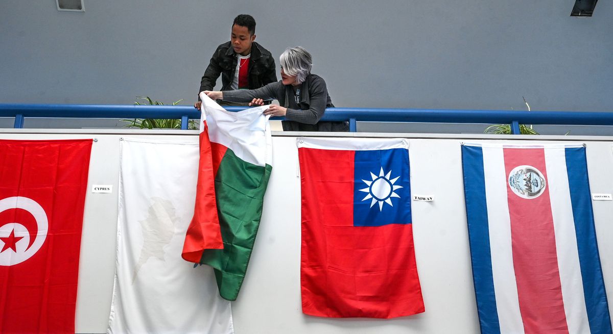 Community Colleges of Spokane Asst. Dean of Global Education Amber McKenzie, right, and Tongasoa Jefferson Julianot Rakotomalala hang the flag of Jefferson