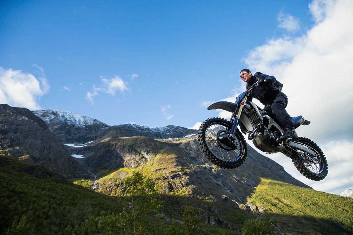 Tom Cruise does his own motorcycle stunt jumping off a ramp on a mountain and skydiving to floor of valley in “Mission: Impossible – Dead Reckoning Part One.”  (Paramount Pictures)