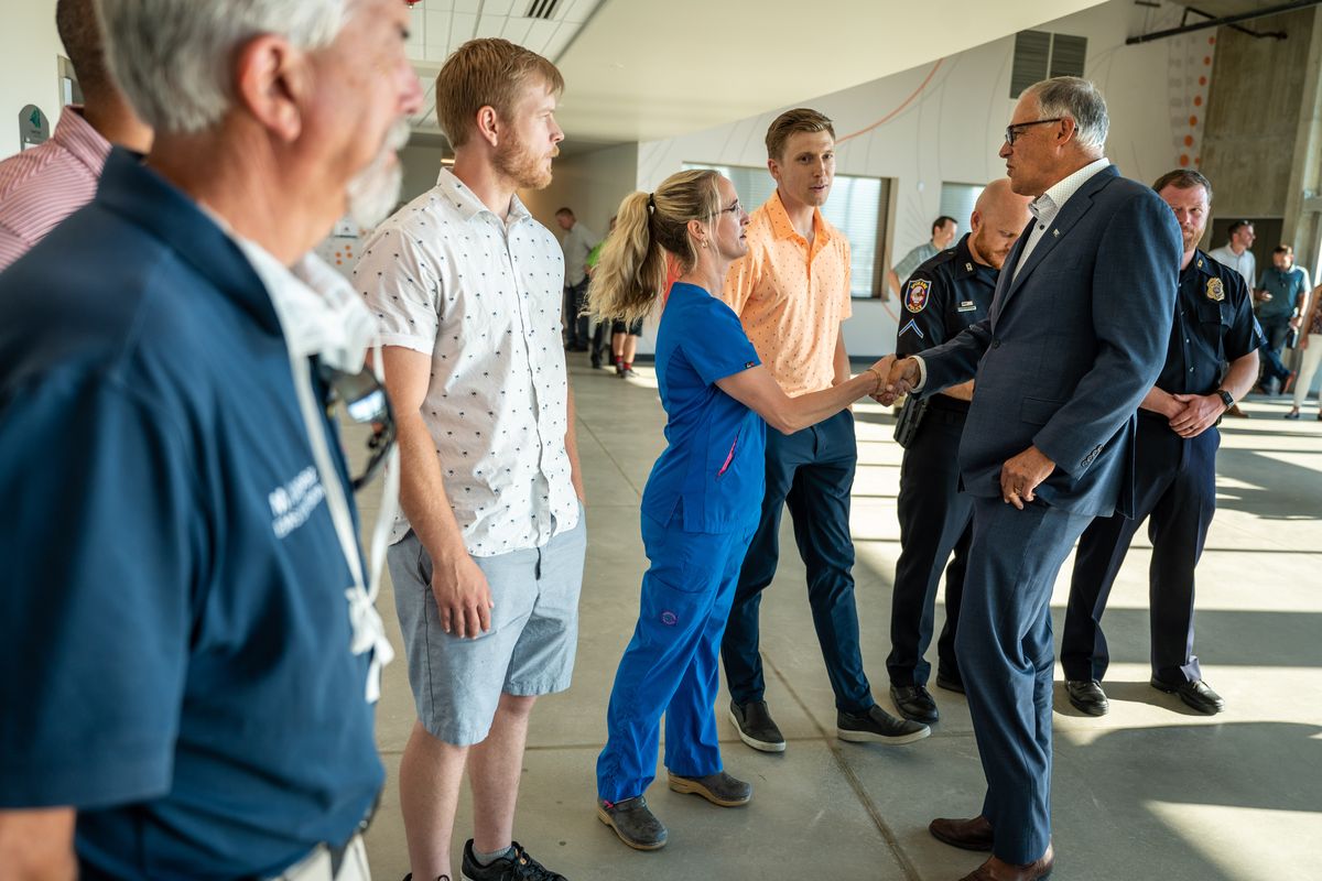 Gov. Jay Inslee greets Stephany Montgomery, an RN manager with MultiCare Valley Hospital and other “Hometown Heroes” before speaking to the press about the lifting of government-imposed COVID-19 restrictions on Wednesday at Riverfront Park.  (COLIN MULVANY/THE SPOKESMAN-REVI)