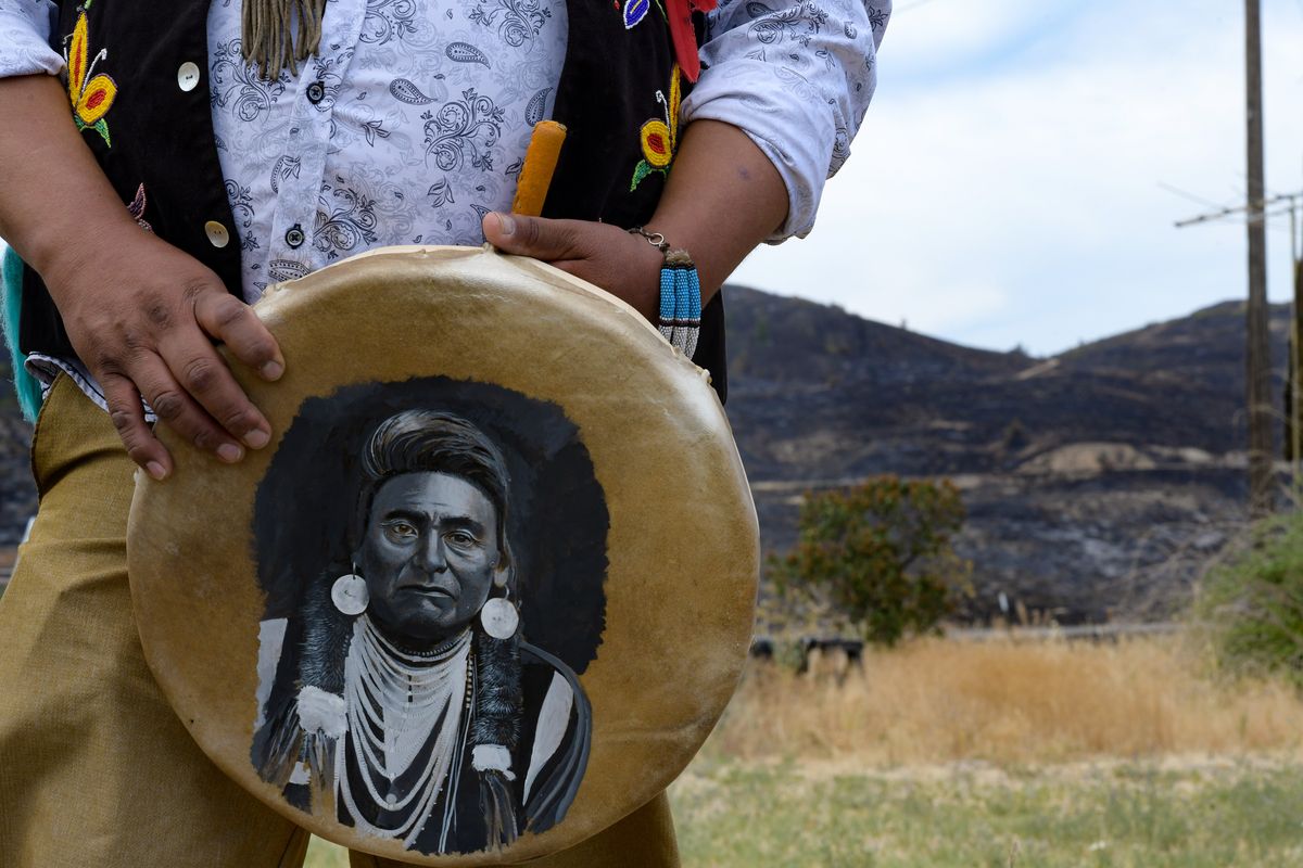 Dan Nanamkin, holds a drum with Chief Joseph painted on it as he describes how the Chuweah Creek Fire crested the ridge behind him Monday night and nearly claimed his home on Friday, July 17, 2021, near Nespelem, Wash.  (Tyler Tjomsland/The Spokesman-Review)