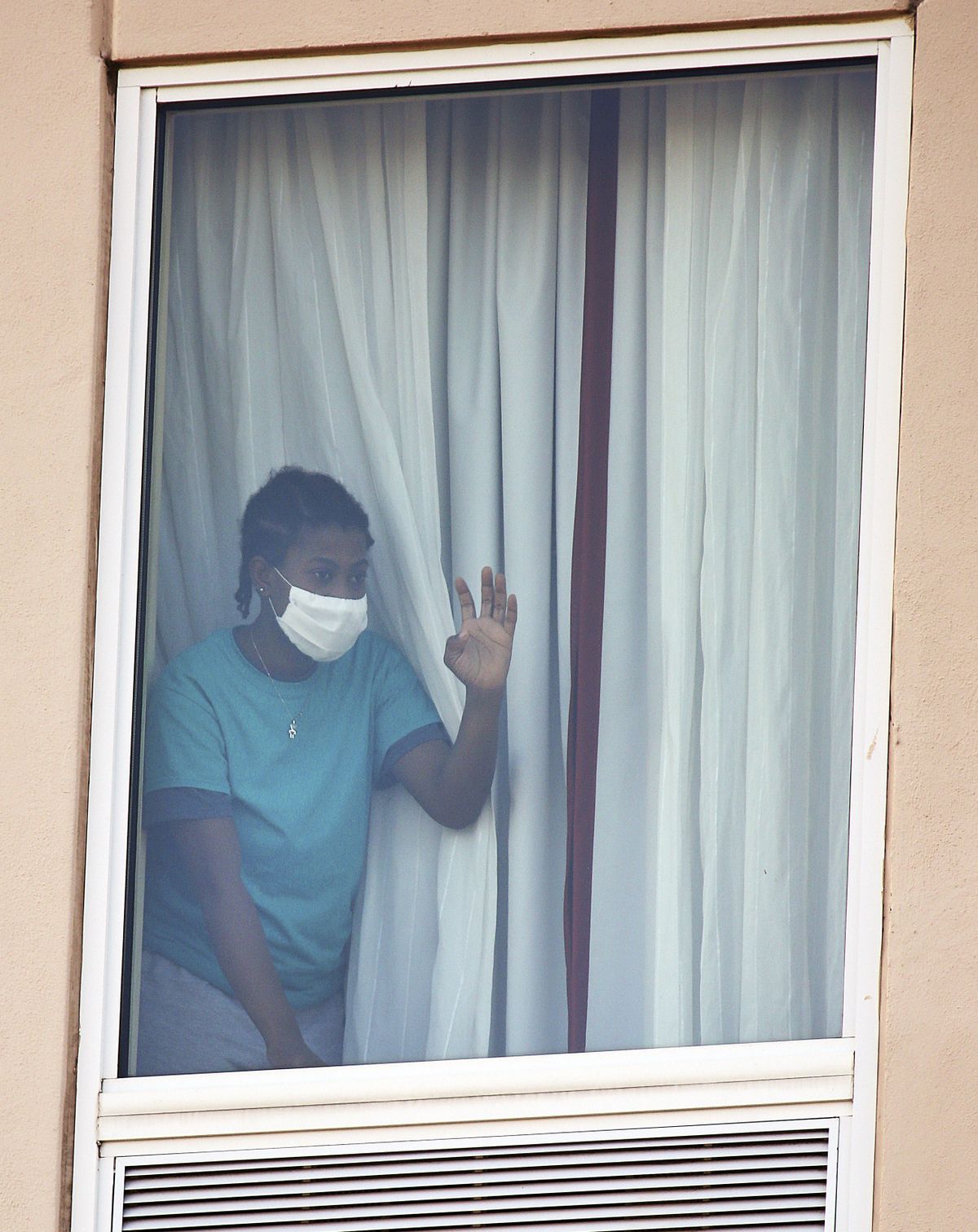 A girl waves from a window on a top floor as protesters wave signs in front of the Hampton Inn hotel on Thursday, July 23, 2020, in McAllen, Texas.  (Joel Martinez/The Monitor via Associated Press)