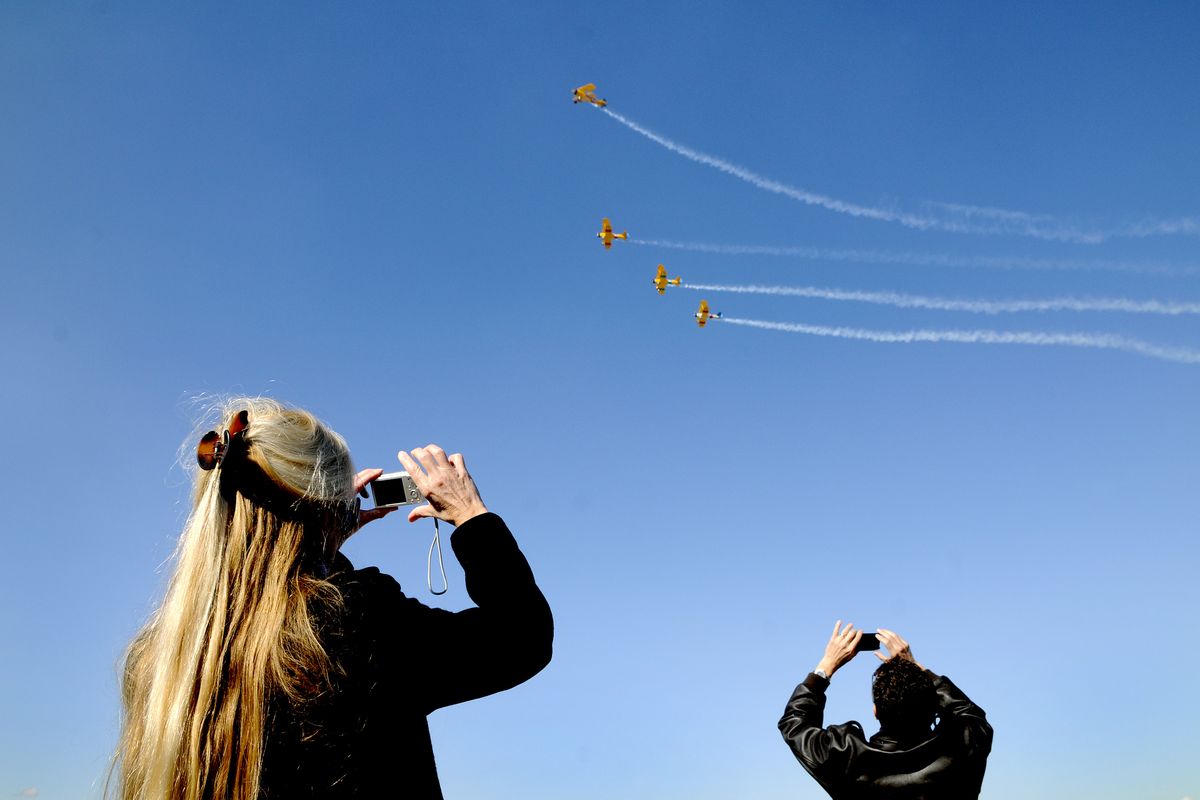 Jacqui Halvorson, left, and David Brukardt snap photos of Stearman aircraft, piloted by Larry Tobin, James Love, David Holmes and Jeff Hamilton, during a celebration ceremony for the opening of an upgraded runway at Spokane International Airport on Saturday. (PHOTOS BY DAN PELLE)