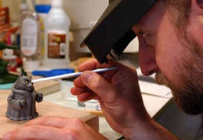 Mike Alsperger fills in the details on his king cat that he molded out of clay. Alsperger has many little figurines that he incorporates into cards.
(Liz Kishimoto / The Spokesman-Review)