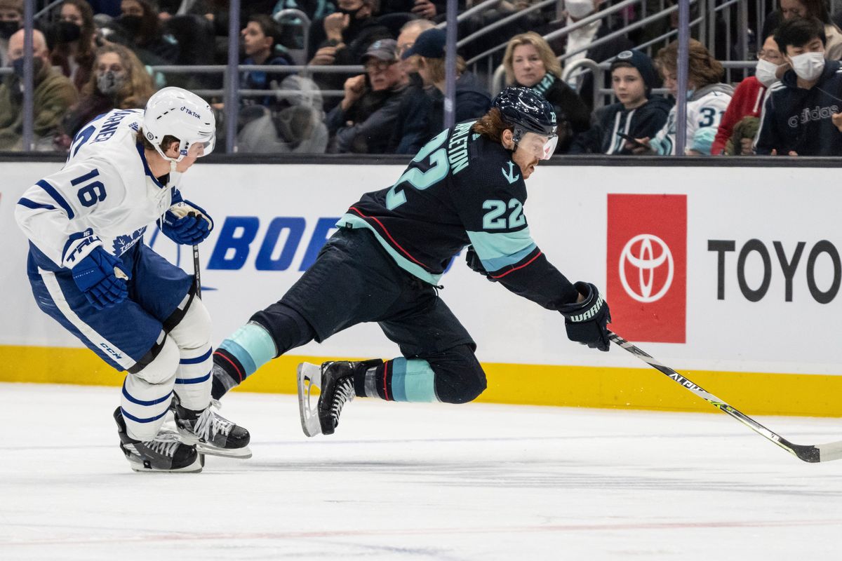 Toronto Maple Leafs right wing Mitchell Marner, left, trips Seattle Kraken center Mason Appleton during the second period of an NHL hockey game, Monday, Feb. 14, 2022, in Seattle.  (Stephen Brashear)