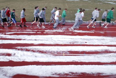 Spring has not yet sprung on the East Valley High running track as the team jogged to warm up Tuesday. Both the baseball and the soccer fields still have patches of snow and ice on them.  (J. BART RAYNIAK / The Spokesman-Review)
