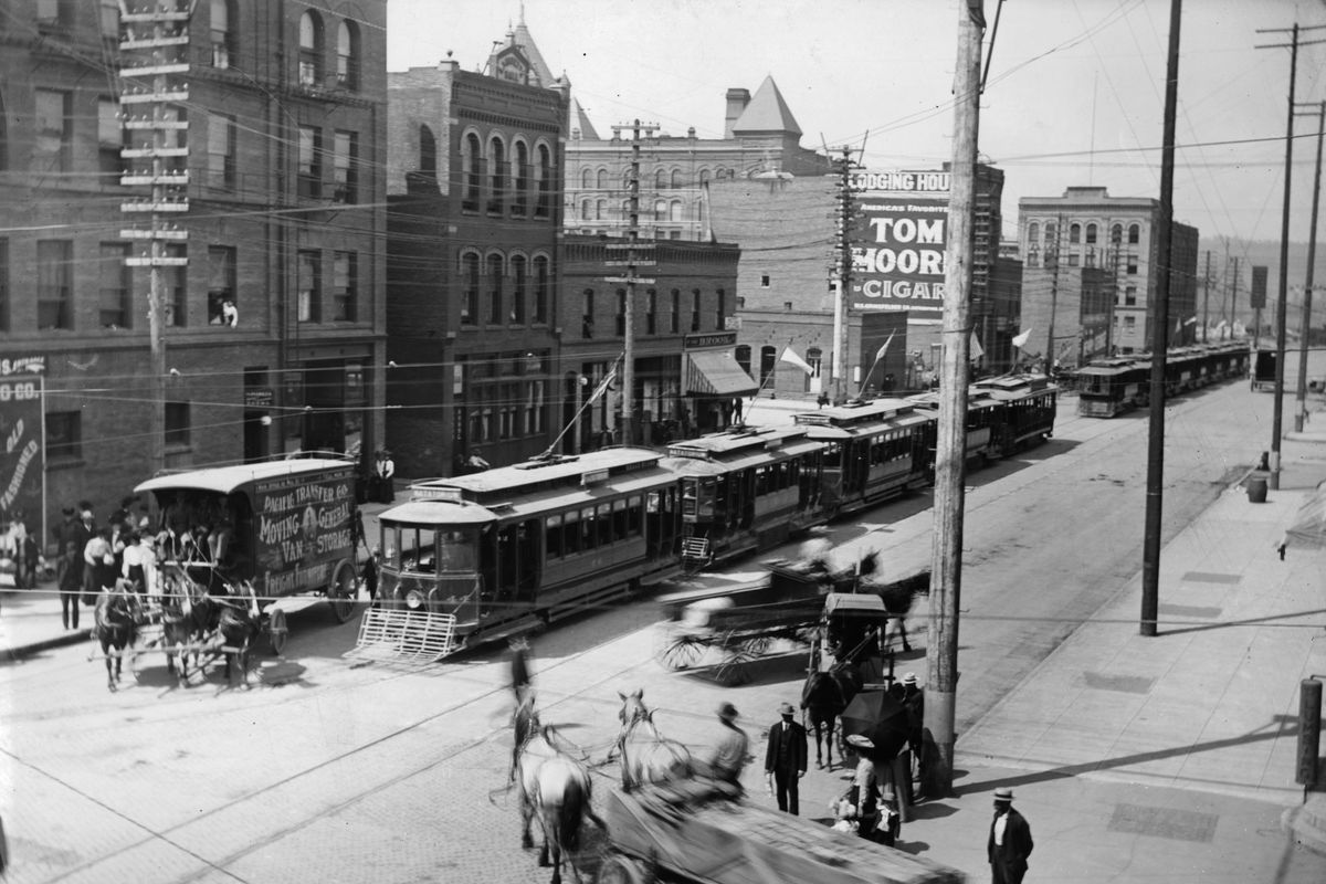 About 1900: Streetcars line up near Trent Avenue and Howard Street, waiting to go to Natatorium Park, as horse-drawn wagons pass by.