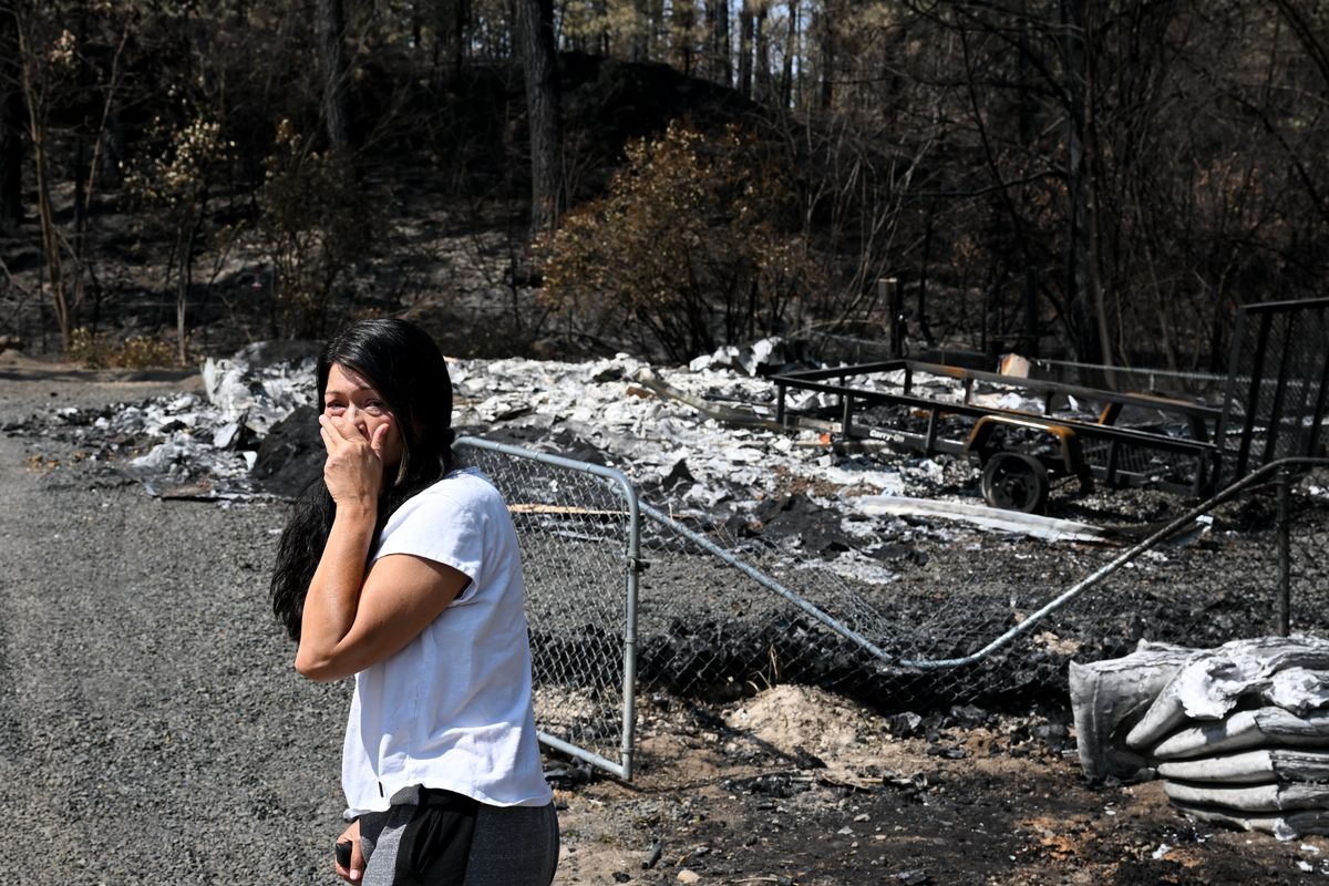 Mary Kaneko, 53, turns away from her burned home and looks to her friend Lisa Hovanec and service dog Akela (not pictured) after getting out of their car and seeing the Silver Lake home for the first time on Aug. 24 after the Gray Fire consumed it near Medical Lake.  (Tyler Tjomsland/The Spokesman-Review)
