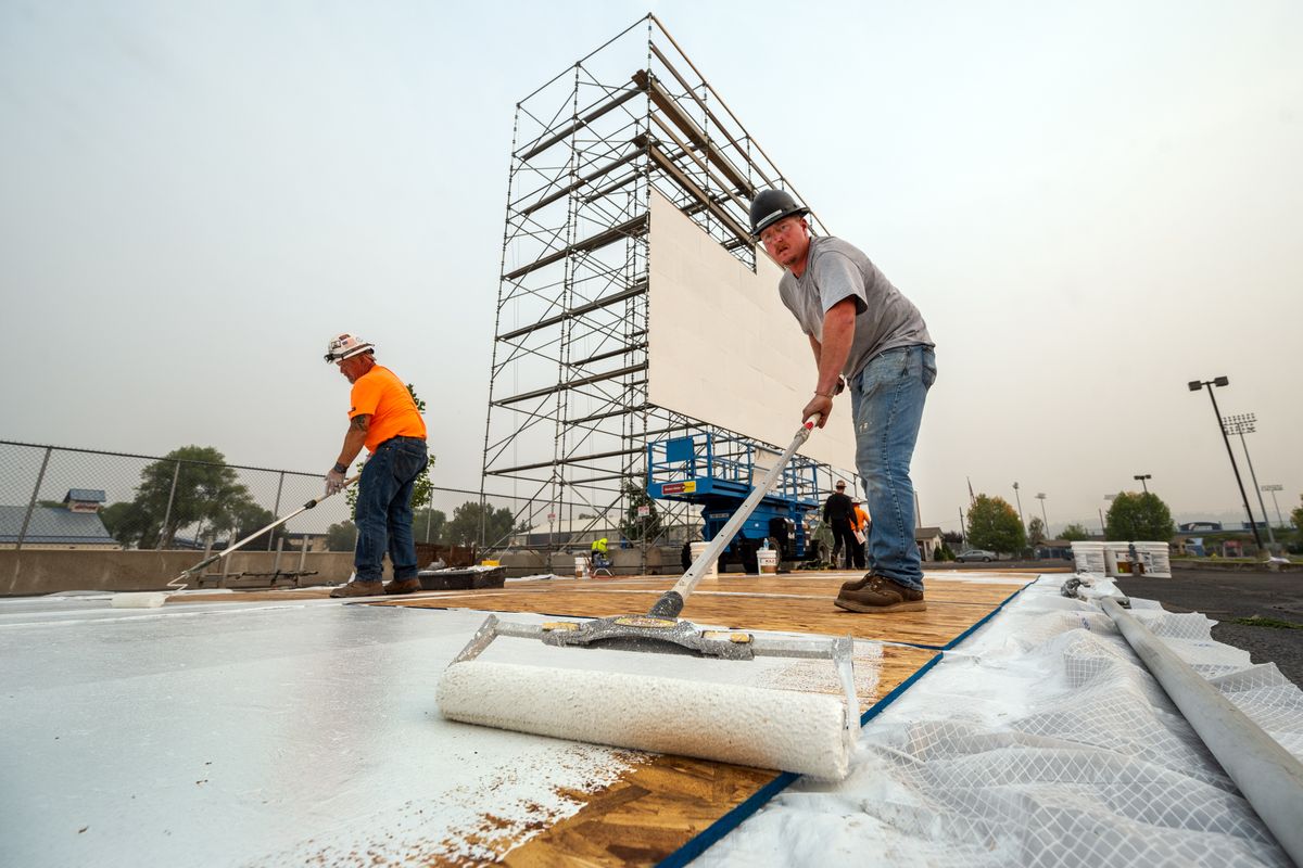 Kelly Bragg, left, and Ryan Ricard, workers with BrandSafway, paint boards white as they help construct a drive-in movie screen in the parking lot of the Spokane County Fair & Expo Center on Wednesday. A New Mexico company is working to bring the drive-in here.  (Colin Mulvany/THE SPOKESMAN-REVIEW)