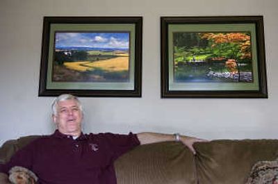 
Doug Oriard sits beneath two of his framed photographs at his  home. He uses computer software to modify the photos to look like paintings. 
 (CHRISTOPHER ANDERSON / The Spokesman-Review)