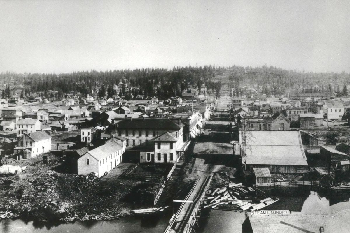 Circa 1886-1889:  Looking south along Howard Street in downtown Spokane, part of the original Howard Street Bridge is seen. At lower right is the roof of the Spokane Steam Laundry. This photo was likely shot from the top floor of the Echo Mill, a four-story building that may have been the tallest in town at the time. Across the river to the left of the bridge is California House, considered to be Spokane’s first hotel. To the right of the bridge was the original store of city father James Glover. (THE SPOKESMAN-REVIEW PHOTO ARCHIVE / SR)
