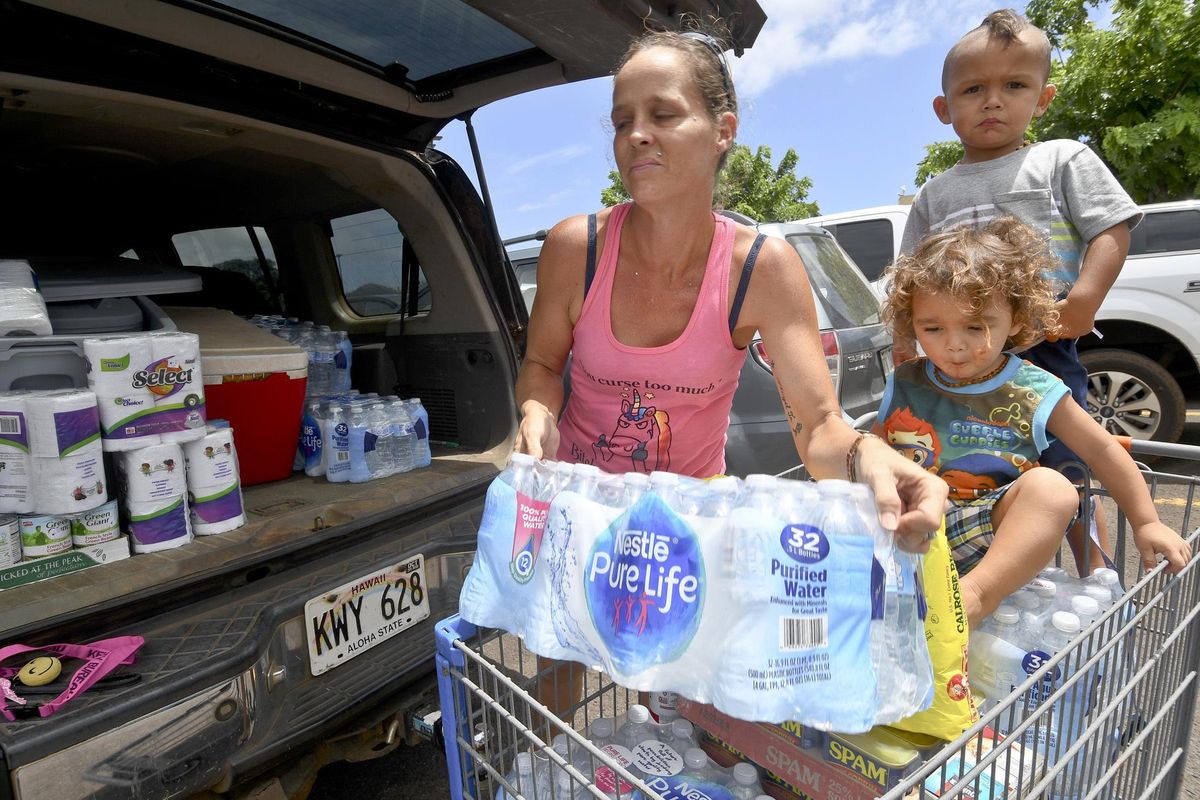 Brianna Sugimura unloads supplies for riding out the storm while her children, Radon-Kai and Kanaloa watch in the parking lot of a Walmart store Tuesday, Aug. 21, 2018, in Lihue, on the island of Kauai in Hawaii. Hurricane Lane “is forecast to move dangerously close to the main Hawaiian islands as a hurricane later this week, potentially bringing damaging winds and life-threatening flash flooding from heavy rainfall,” the weather service’s Central Pacific Hurricane Center warned as it got closer to the state. (Dennis Fujimoto / AP)
