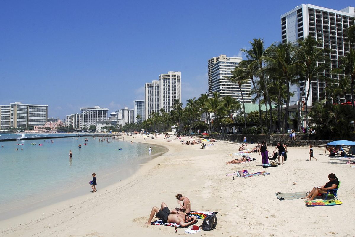 In this March 13, 2017, file photo, people relax on the beach in Waikiki in Honolulu. Many Americans might dream of going on vacation to places such as Waikiki, but a new poll shows nearly half of Americans won