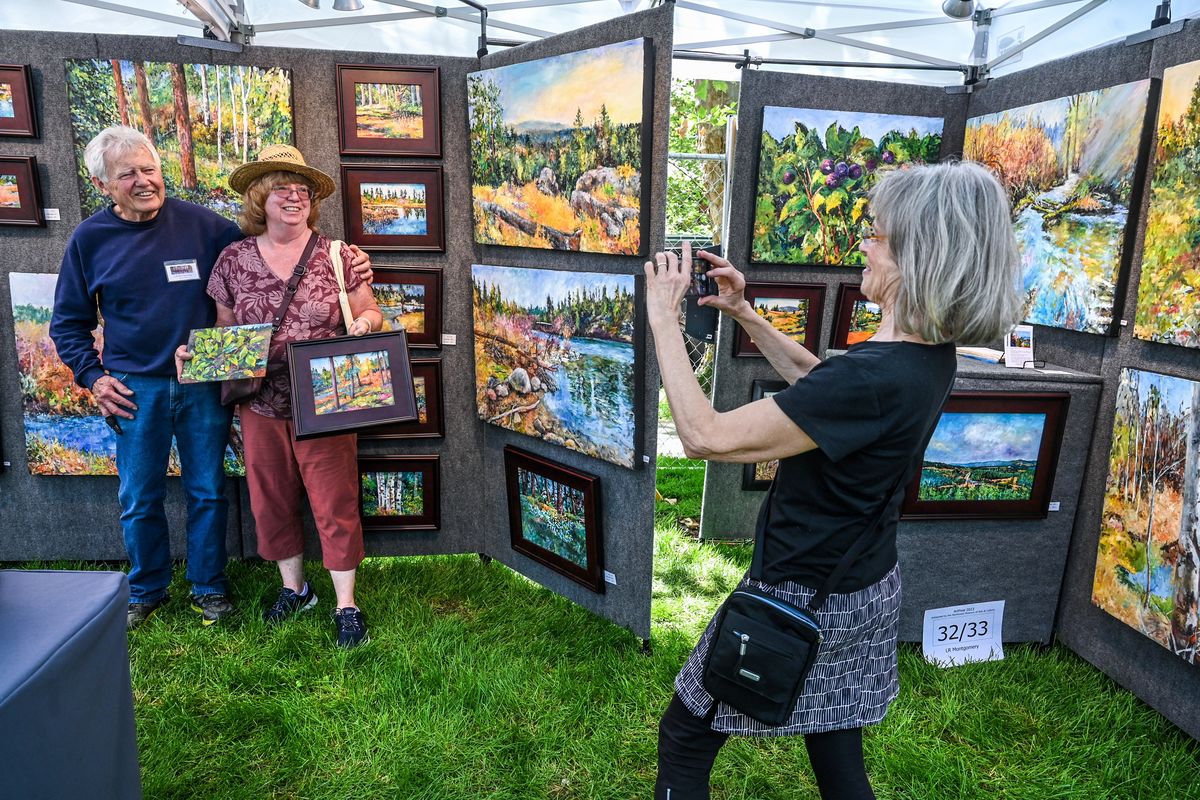 Carole Montgomery, right, snaps a picture of her artist husband, LR Montgomery, left, of Spokane, and Maureen Carl, of Bayview, Idaho, after Carl found some oil paintings during the 38th ArtFest on Friday at the Museum of Arts & Culture in Spokane. Carole sends snapshots to customers as a thank you. Carl says she has been waiting four years to find the right piece.  (DAN PELLE/THE SPOKESMAN-REVIEW)