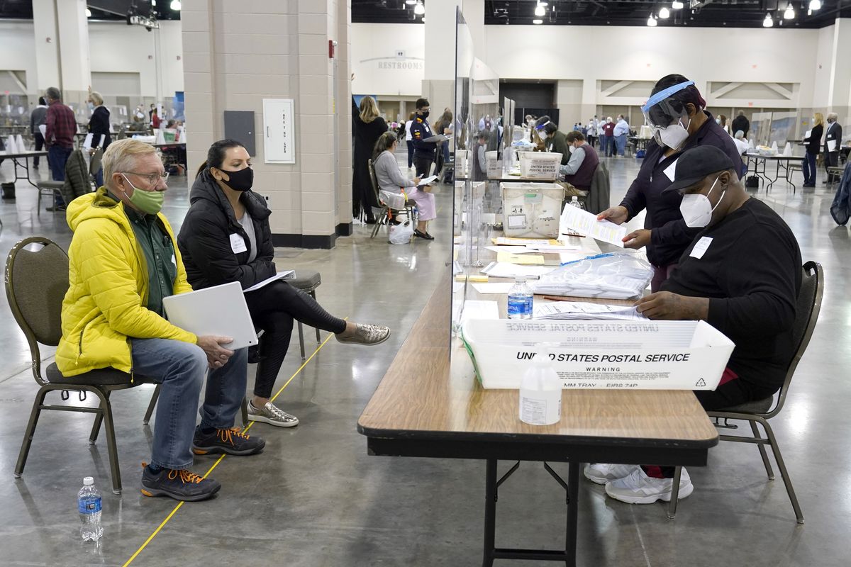 Election workers, right, verify ballots as recount observers, left, watch during a Milwaukee hand recount of presidential votes at the Wisconsin Center, Friday, Nov. 20, 2020, in Milwaukee. The recount of the presidential election in Wisconsin’s two most heavily Democratic counties began Friday with President Donald Trump’s campaign seeking to discard tens of thousands of absentee ballots that it alleged should not have been counted.  (Nam Y. Huh)