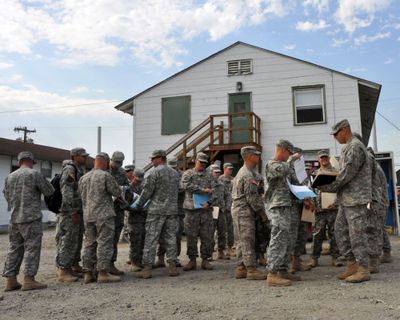 Members of Charlie Company check folders containing mandatory paperwork outside their World War II-era barracks at Joint Base Lewis-McChord on Thursday. (Jim Camden)