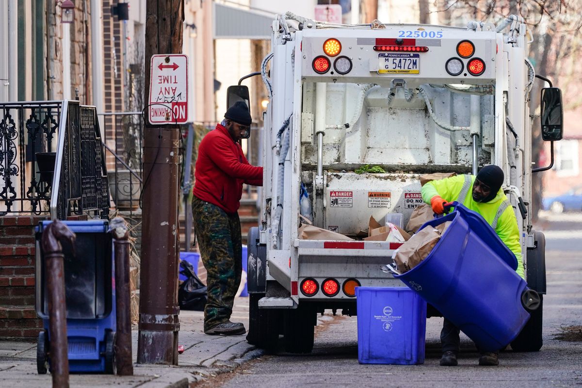 Municipal sanitation workers collect trash in Philadelphia, Thursday, Jan. 13, 2022. The omicron variant is sickening so many sanitation workers around the U.S. that waste collection in Philadelphia and other cities has been delayed or suspended.  (Matt Rourke)