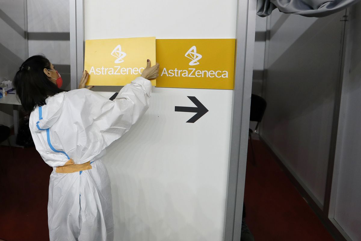 A medical worker wearing protective gear sets up boards with the names of the vaccines on Sunday at a vaccination center in Belgrade, Serbia.  (Darko Vojinovic)