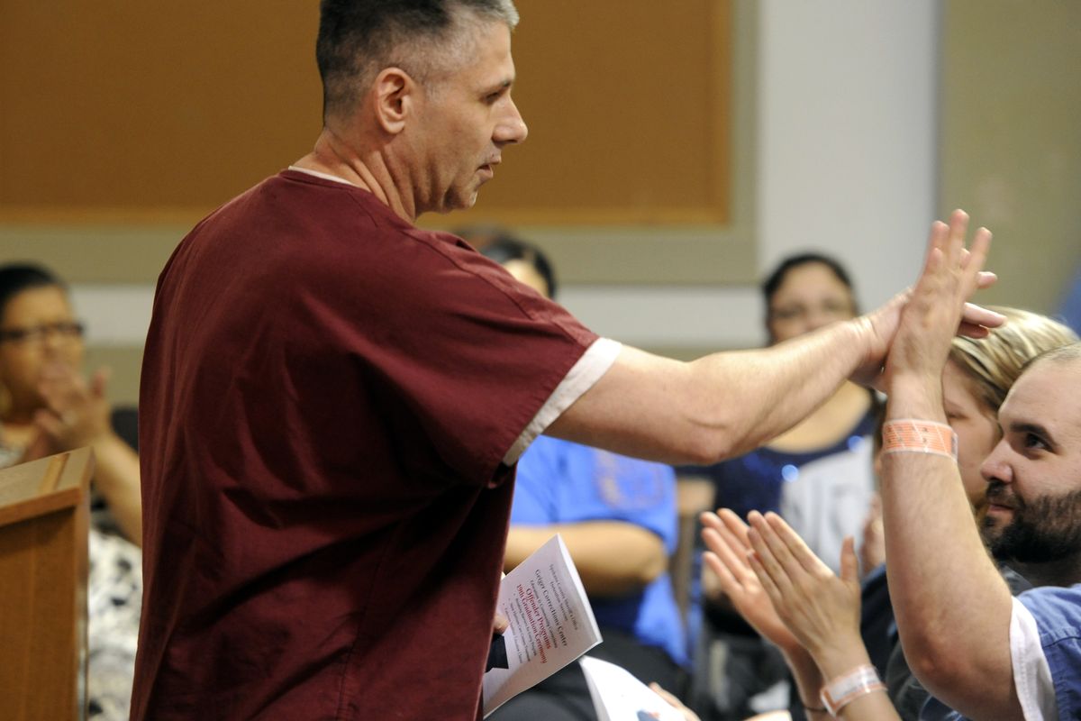 Mark Bliven, left, high-fives Chuck Bliss on Thursday after making a short speech about how his life has been affected by classes at Geiger Correctional Facility. The county lockup offers counseling and life skills classes through the Fulcrum Institute. (Jesse Tinsley)