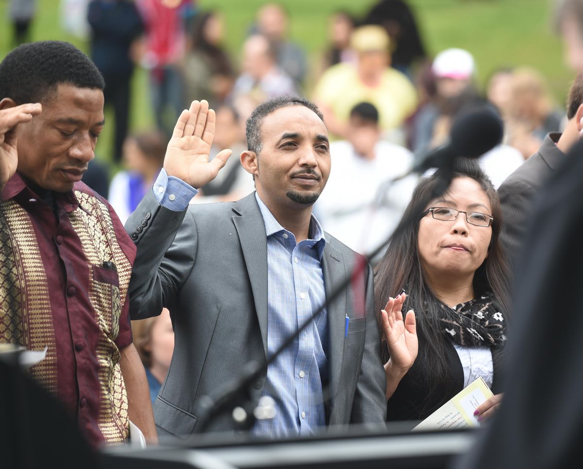 Merih Gebrehiwot, center, of Eritrea, recites the oath of citizenship that  was administered by Judge Thomas Rice in Liberty Park on Saturday, June 18, 2016, during a gathering to celebrate World Refugee Day. The event also included speakers, live music and dance and a free sampling of foods from around the world. (Jesse Tinsley / The Spokesman-Review)