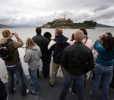 Visitors take pictures from the prow of a boat to Alcatraz Island for an evening tour of the historical island prison in San Francisco Bay.