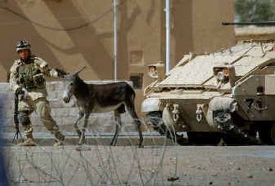 
A U.S. soldier moves a donkey away from an armored vehicle Friday during a cease-fire held for negotiations with Muqtada al-Sadr in the holy city of Najaf, Iraq. 
 (Associated Press / The Spokesman-Review)