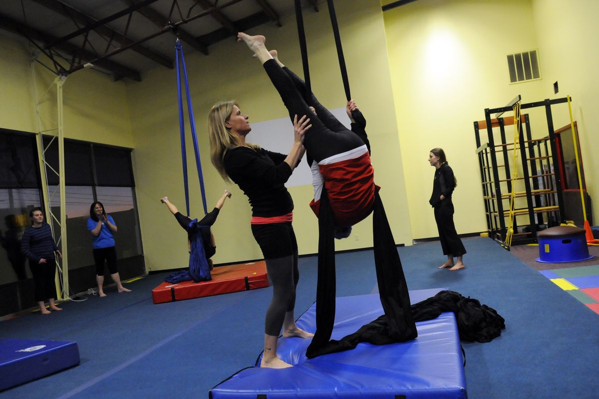 Spokane Aerial Performance Arts founder and instructor Sherrie Martin works with Carolyn Kinghorn on Dec. 4 as she attempts an arrow maneuver while hanging upside down on long pieces of silk fabric. (J. Bart Rayniak)