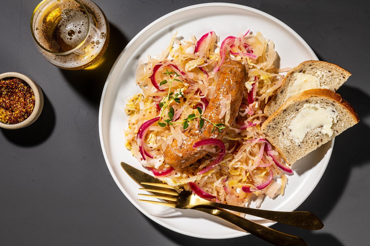 Sheet pan sausages with sauerkraut and mustard can be served family-style and with crusty bread. (Rey Lopez/For the Washington Post)