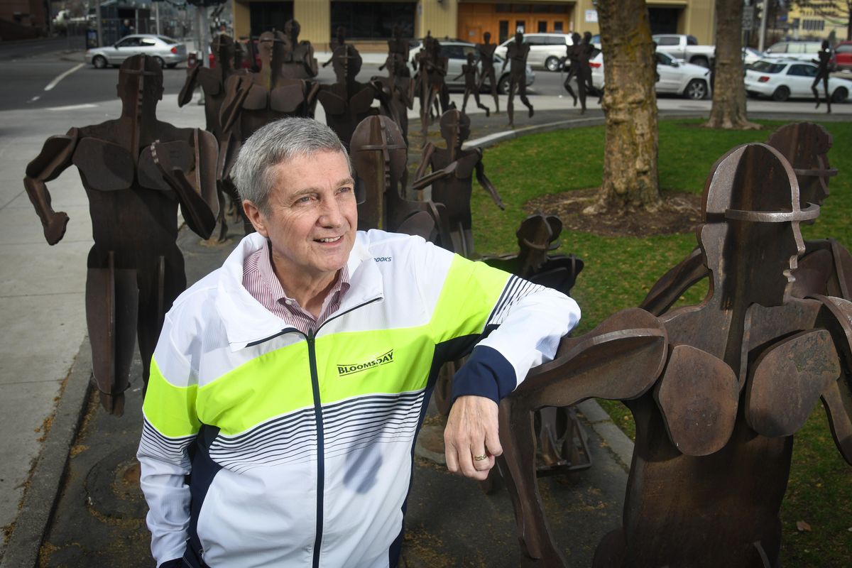 Bloomsday race director Don Kardong is retiring. Here he stands at the corner of Spokane Falls Blvd. and Post Street with “The Joy of Running Together” statues in Riverfront Park. (Dan Pelle / The Spokesman-Review)