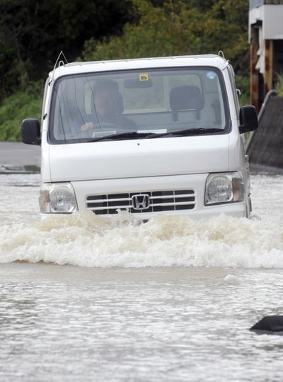 A man drives a car on a flooded street in Kihocho, Wakayama prefecture, western Japan, on Wednesday. (Associated Press)