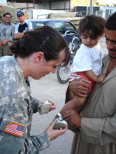 
Capt. Laurissa Commers puts a pair of donated sandals on the feet of an Iraqi toddler. The Army reservist, who is serving near Baghdad, said poverty is widespread and people often lack essentials.
 (Courtesy of Laurissa Commers / The Spokesman-Review)