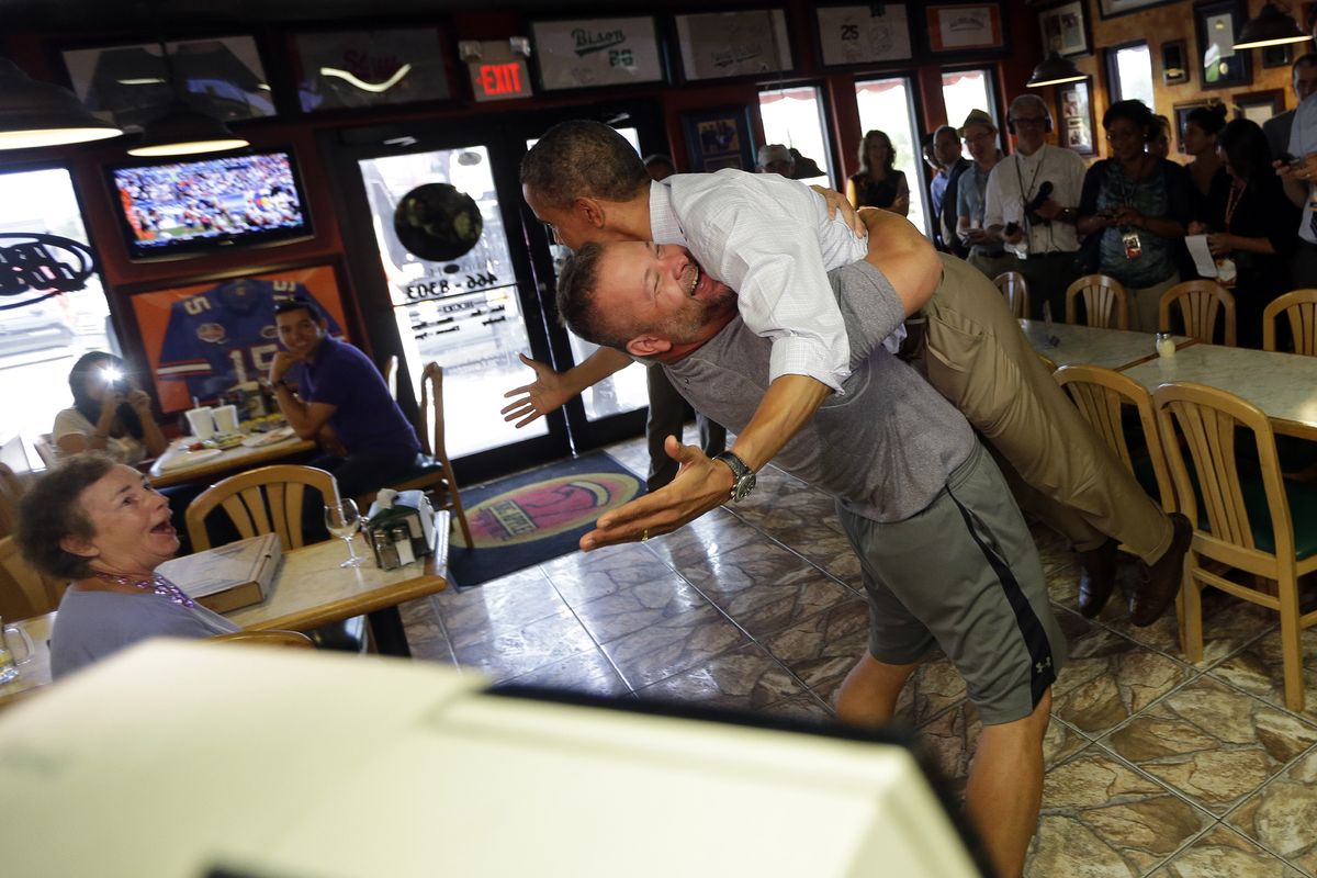 President Barack Obama, right, is picked-up and lifted off the ground by Scott Van Duzer, left, owner of Big Apple Pizza and Pasta Italian Restaurant during an unannounced stop, Sunday, Sept. 9, 2012, in Ft. Pierce, Fla. (Pablo Monsivais / Associated Press)