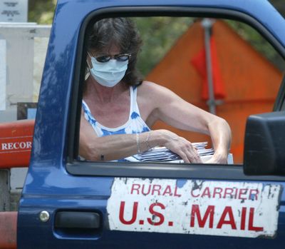 Virginia Beaudry picks up her mail Monday before heading back to the remains of her home in Concow, Calif.  (Associated Press / The Spokesman-Review)