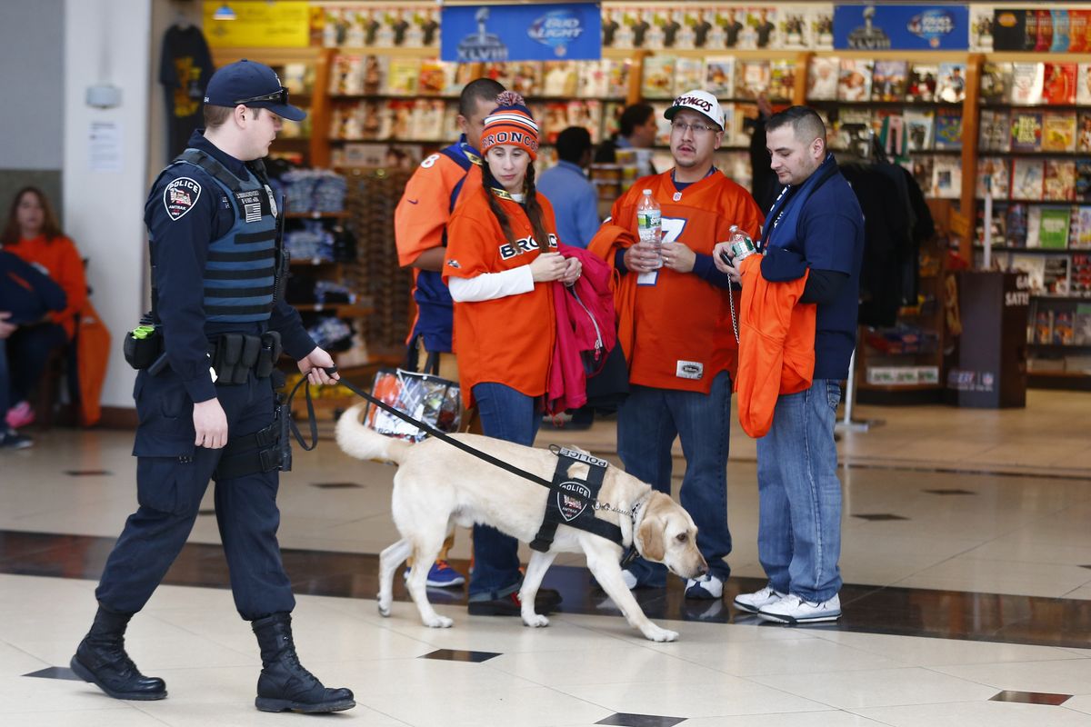 A police officer and his dog walk past football fans at the Secaucus Junction, Sunday, Feb. 2, 2014, in Secaucus, N.J. The Seattle Seahawks are scheduled to play the Denver Broncos in the NFL Super Bowl XLVIII football game on Sunday, earning MetLife Stadium in East Rutherford, N.J. (Morry Gash / Associated Press)