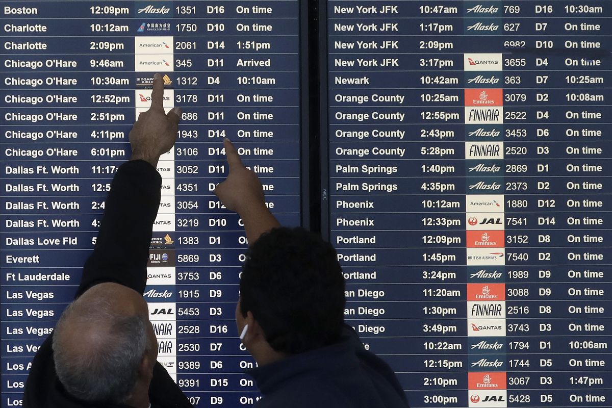FILE - Two men point toward plane arrivals on a flight information board at San Francisco International Airport in San Francisco, Tuesday, Nov. 26, 2019. Forecasters say, Friday, March 11, 2022, a powerful, late-winter storm combining rivers of moisture and frigid temperatures is expected to dump snow from the Deep South all the way north to the Canadian border over the weekend that could cause travel problems and power outages across a wide part of the Eastern United States from late Friday through early next week.  (Jeff Chiu)