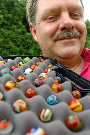Scott  Shupe poses with dozens of marbles from his collection Friday, July 15, 2005.  Shupe has more than 300,000 marbles in his collection.  (Joe Barrentine / The Spokesman-Review)