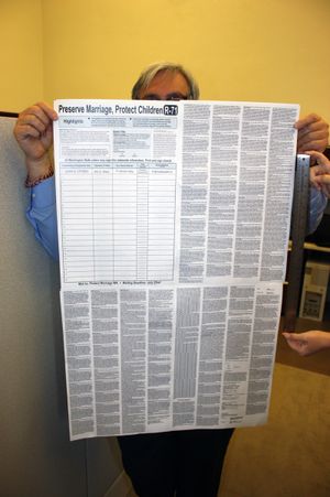David Ammons of the Washington Secretary of State's office holds a copy of Referendum 71, which must fit about 114 pages of a legislative bill onto a single sheet of paper. (Washington Secretary of State)
