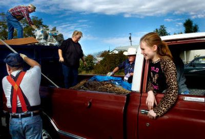
Ashley Robinson  watches from the cab of her grandmother Bonny Morris' truck while, clockwise from bottom left, Ken Tinkham, Curt Bagly, Morris and Bob Grinnell unload the pickup. 
 (Amanda Smith / The Spokesman-Review)