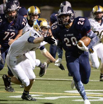 Mt. Spokane's Dakota Hipes busts past Mead's Hayden Johnson, left, in the rivalry game. Hipes led the Wildcats with 85 rushing yards. (Jesse Tinsley)