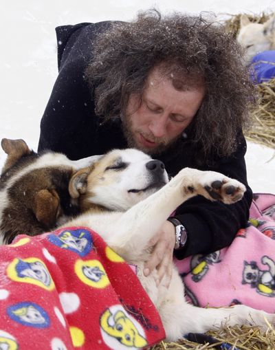 Sebastian Schnuelle, from Whitehorse, Yukon, plays with his dogs Gas, left, and Diesel during a rest stop at Takotna, Alaska. (Associated Press / The Spokesman-Review)